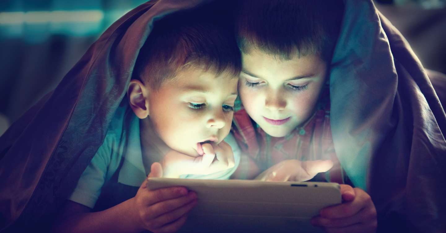two kids looking at a tablet at night