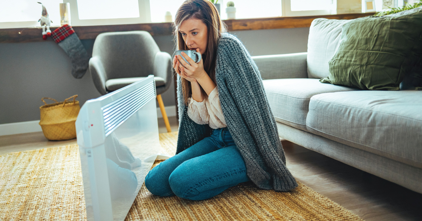 woman by a heater in a house with no heat