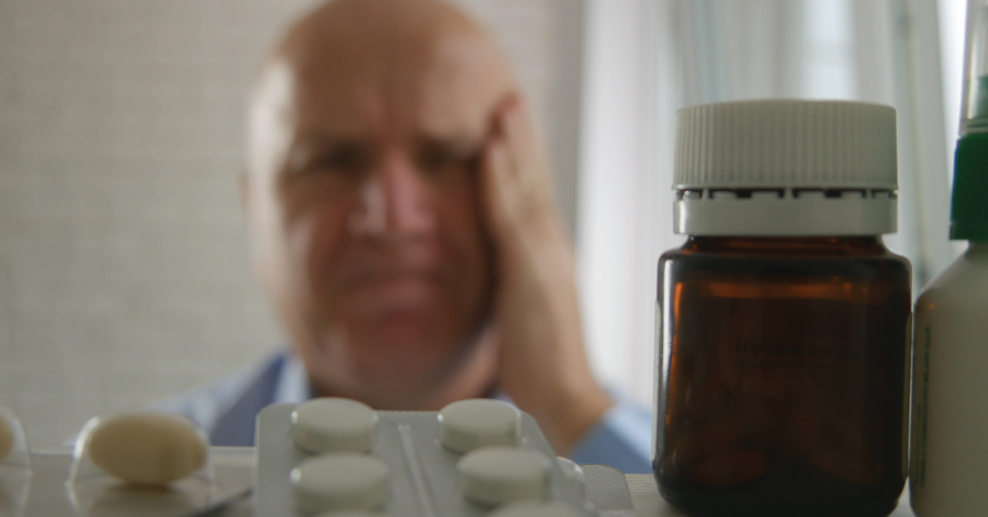 a person in front of their medicine cabinet trying to decide which medicine to use to treat their cold and flu symptoms