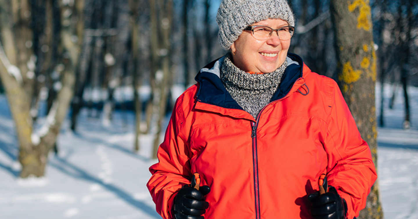 woman in red coat standing in forest while skiing