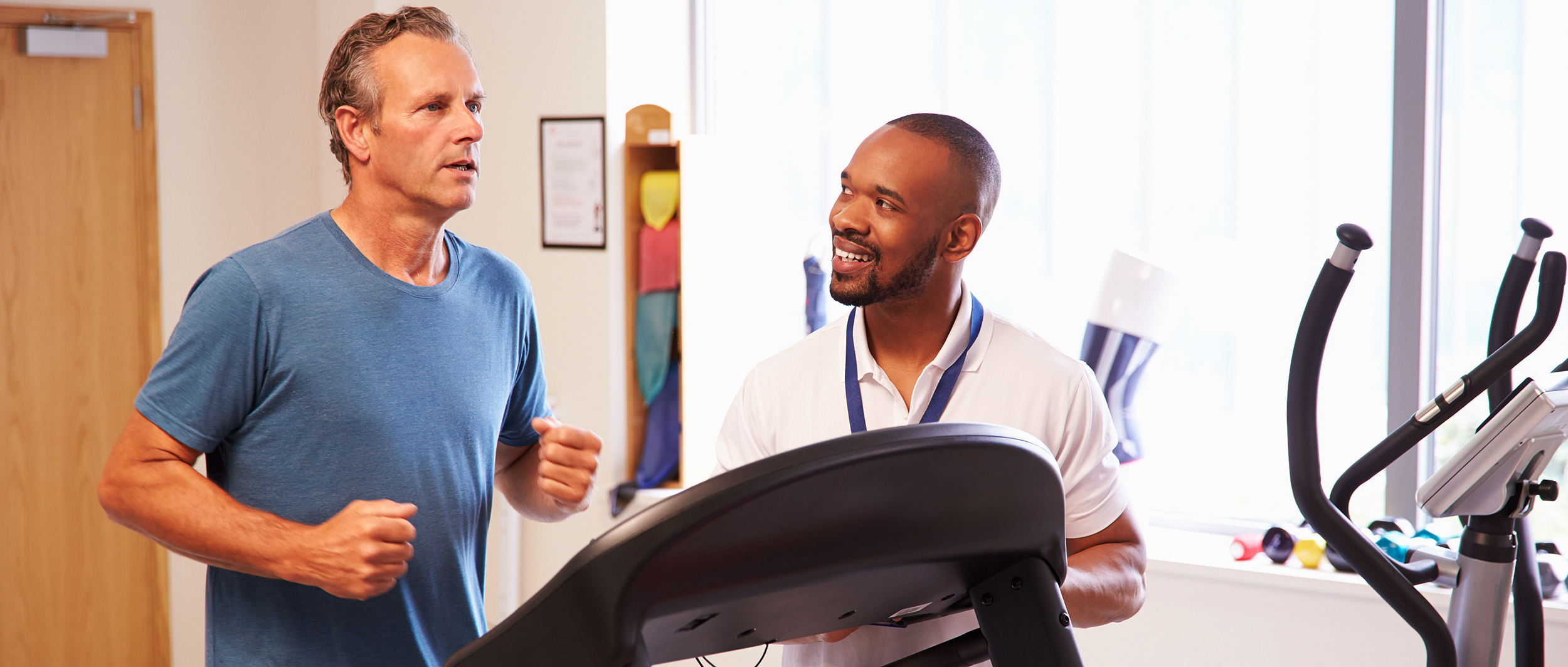 man running on treadmill being consulted by doctor
