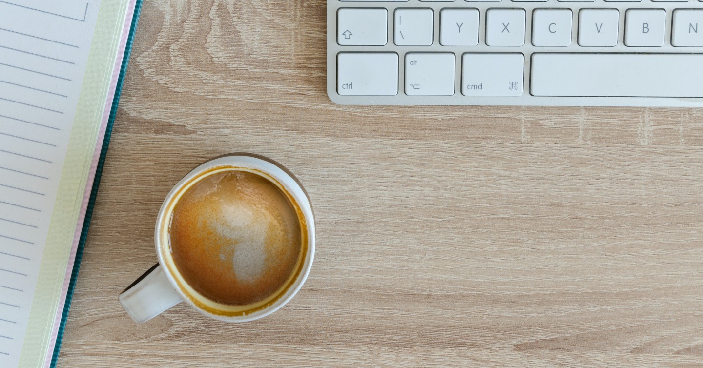 coffee cup next to notebook and laptop for online learning