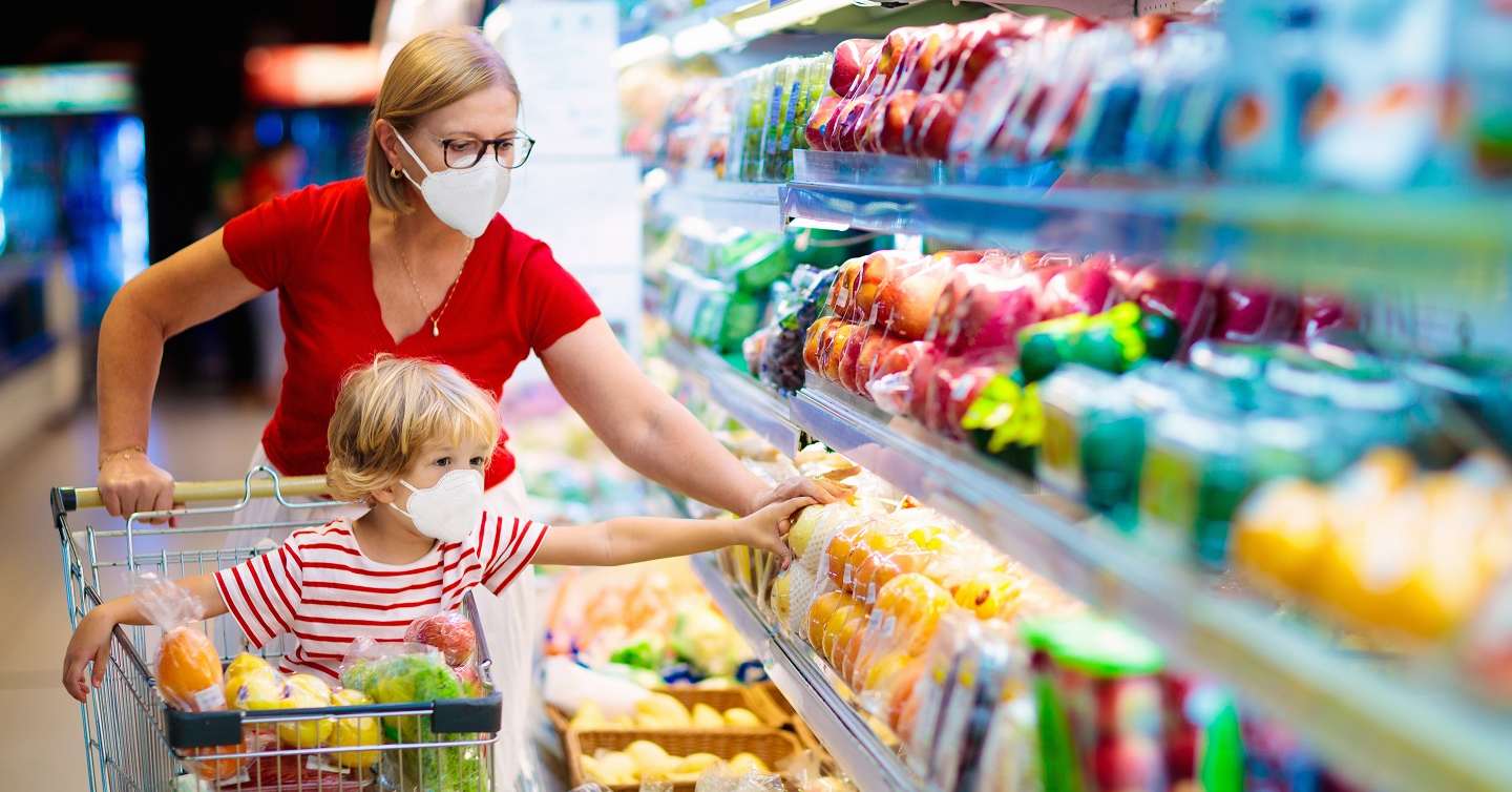 mother and young son in shopping cart donning virus-resistant masks