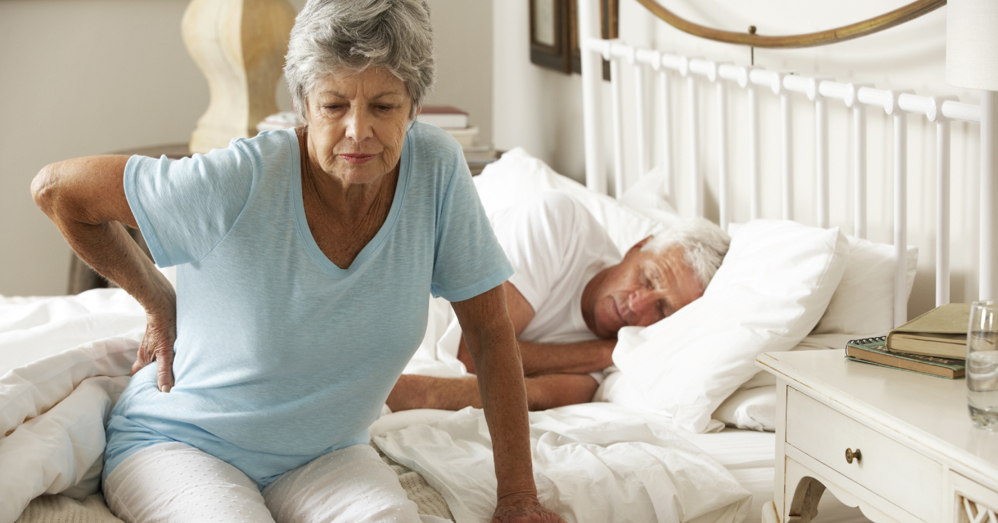 a woman experiencing pain and struggling to get out of bed