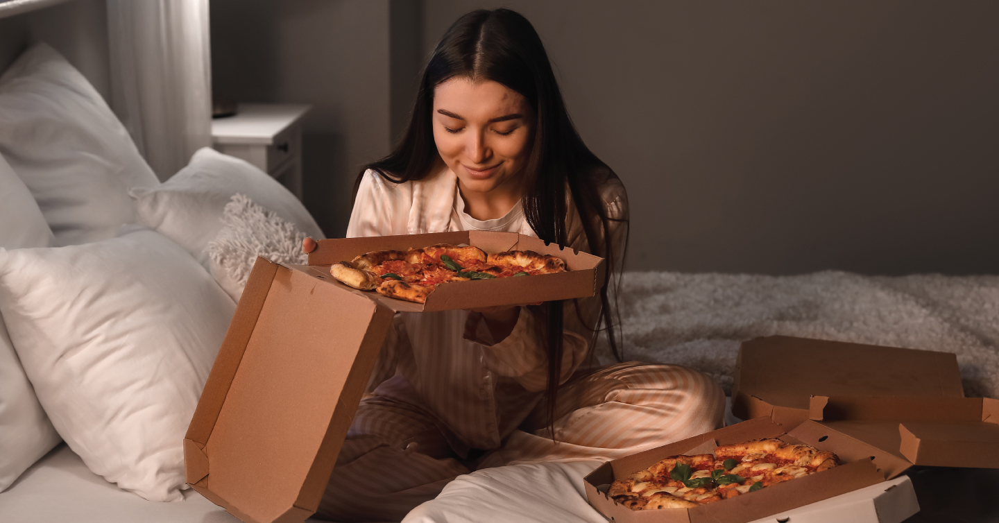 a woman eating a pizza in bed