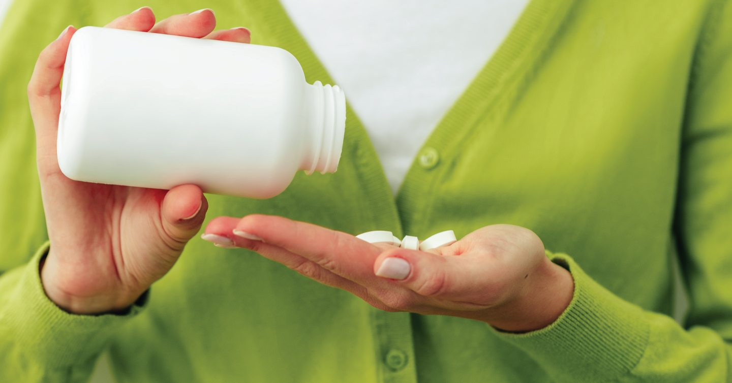 person portioning a bottle of aspirin into their hand