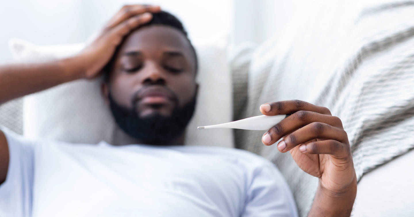 man lying in bed with a thermometer
