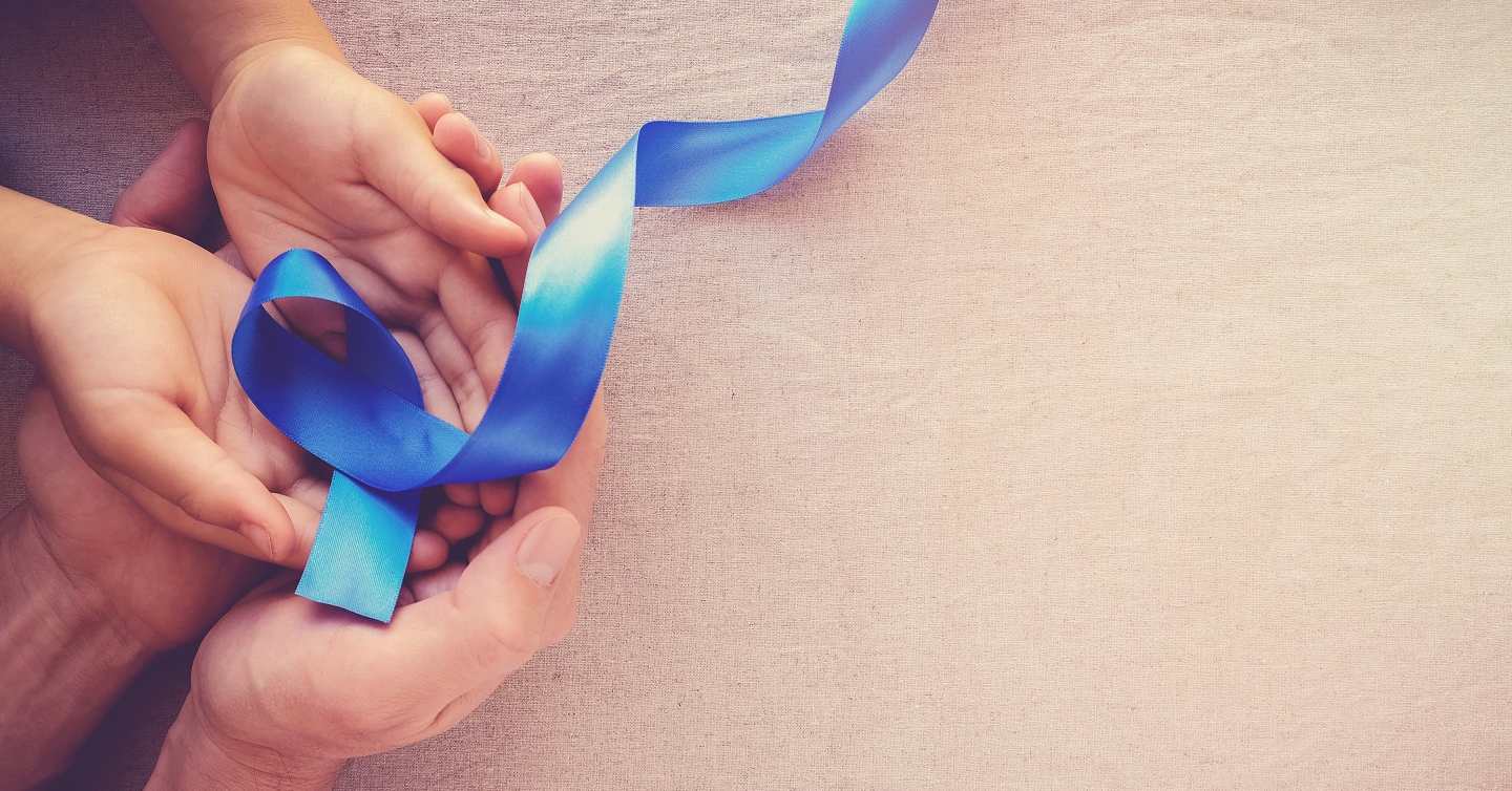 hand holding ribbon for colorectal cancer