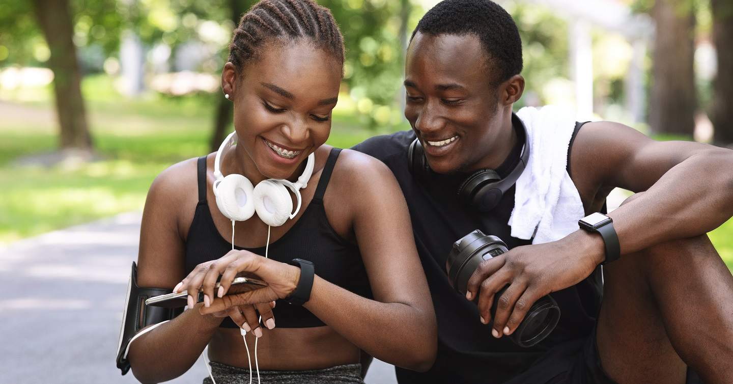 younger couple checking their fitness trackers during an exercise session