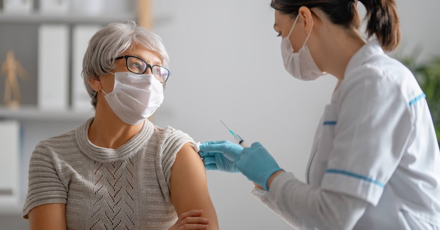 woman receiving flu shot by doctor in home