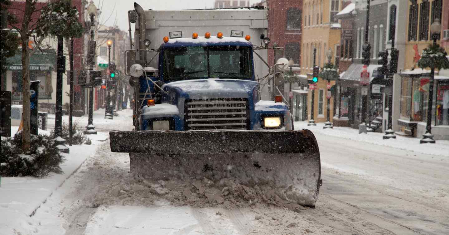 snow plow driving down small town street