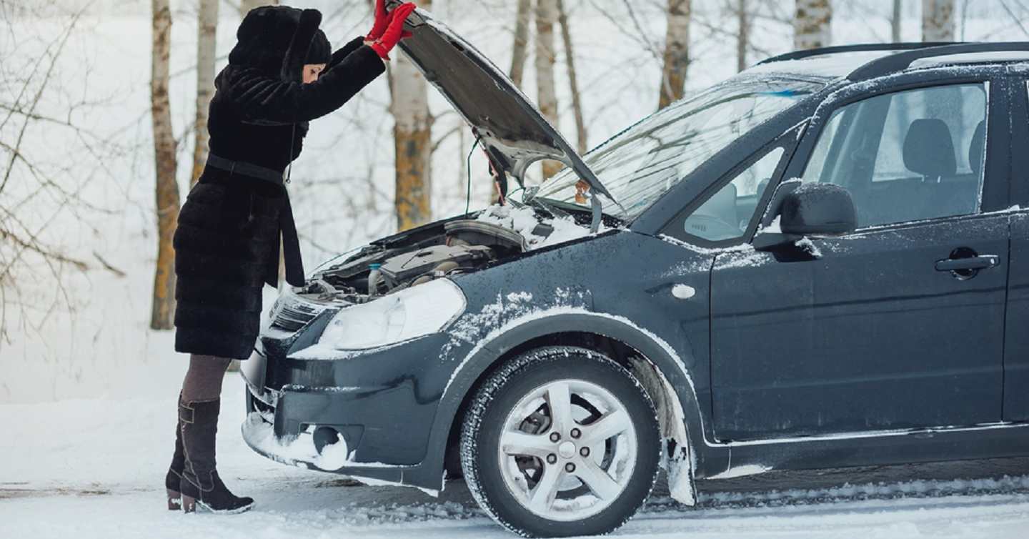 woman checking her car engine bay for issue during winter