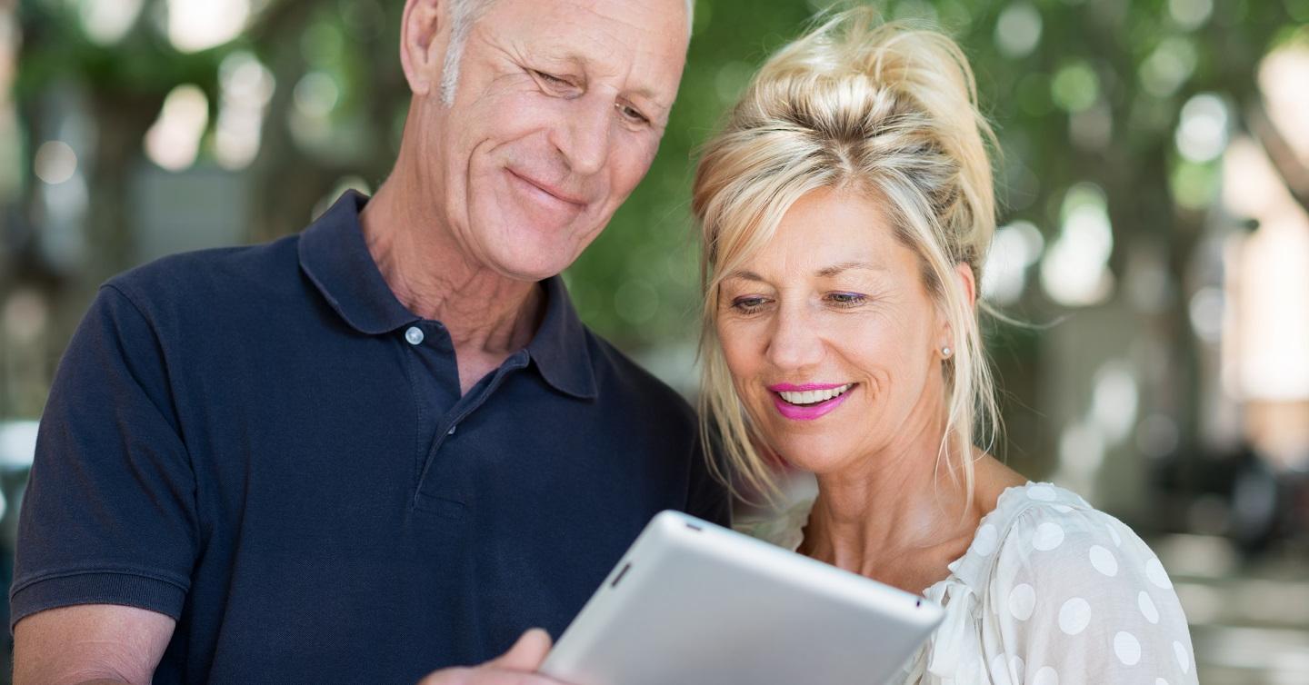 senior couple reading health information on ipad outside